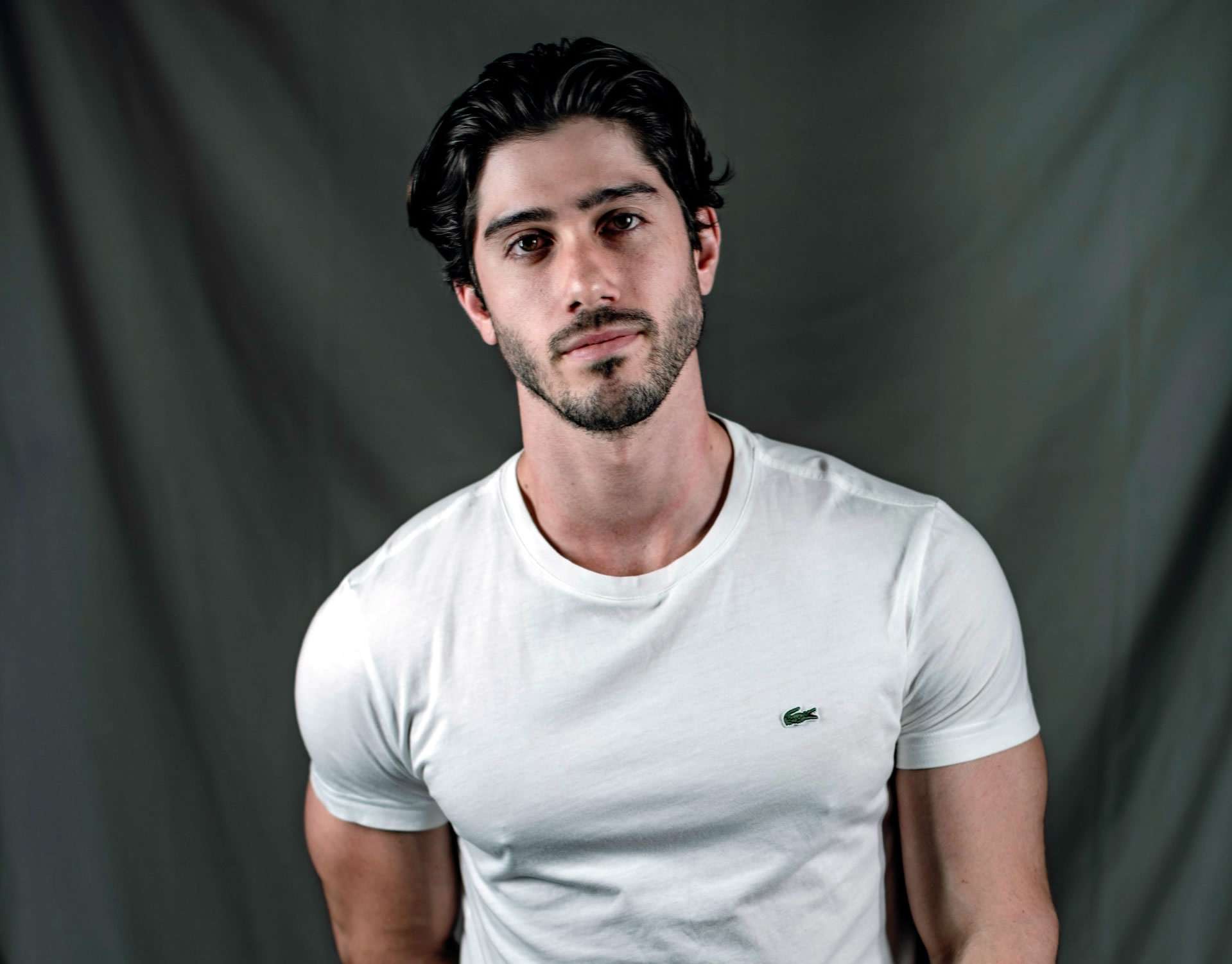 A man wearing a tight white t-shirt with a stubble with styled hair